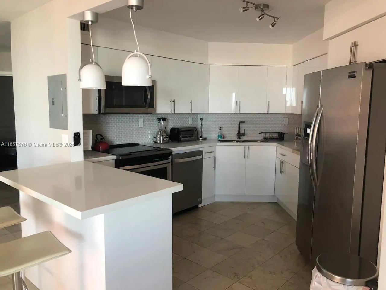 5161 Collins Avenue, Unit 1104 Miami Beach, FL 33140 - Photo 7 of 19 a kitchen with stainless steel appliances granite countertop a sink a stove and a refrigerator