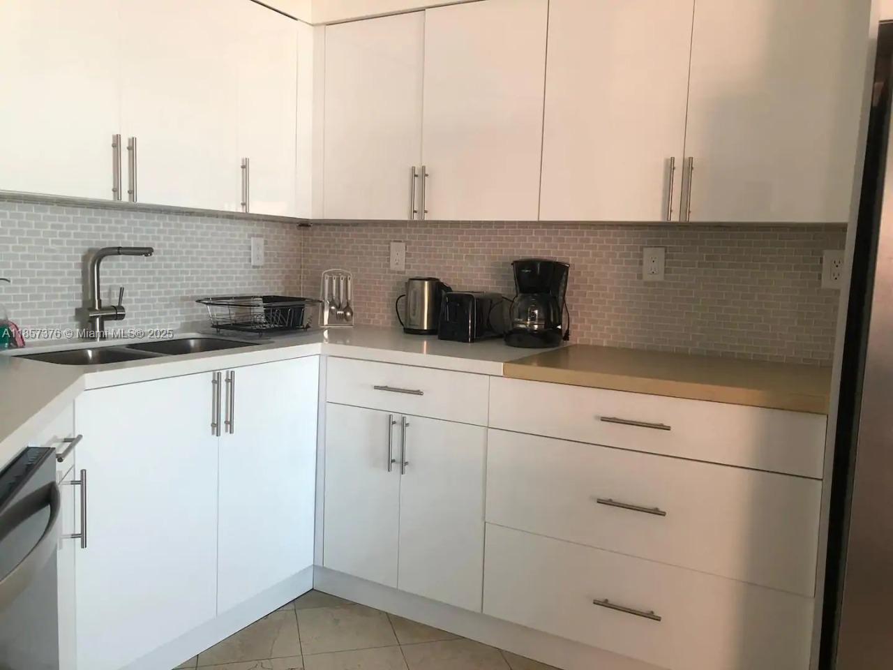 5161 Collins Avenue, Unit 1104 Miami Beach, FL 33140 - Photo 9 of 19 a kitchen with granite countertop white cabinets and white appliances