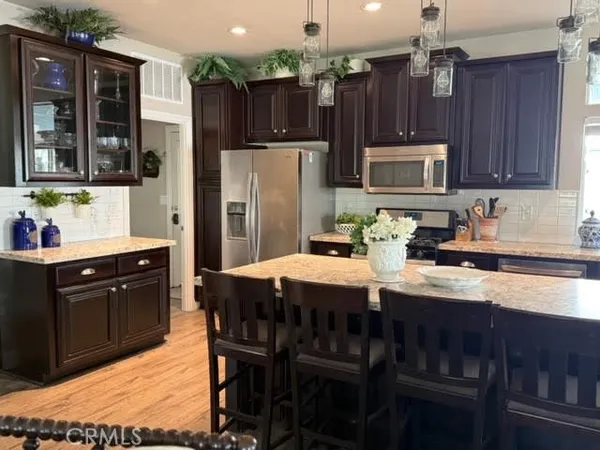 a kitchen with stainless steel appliances granite countertop a refrigerator a stove a sink dishwasher and wooden cabinets with wooden floor