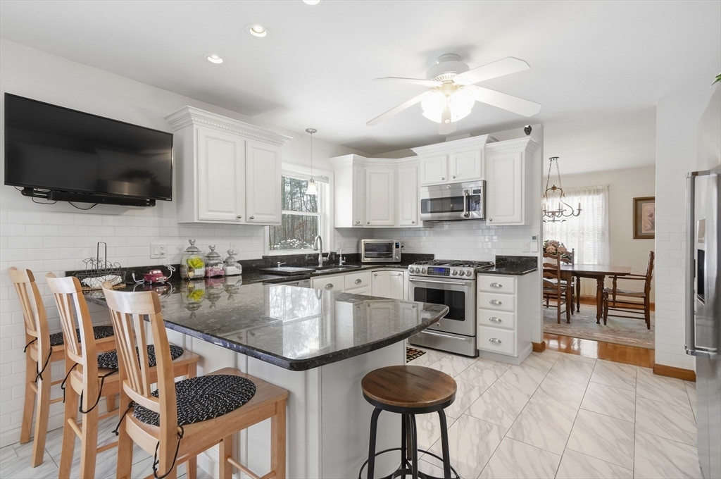 459 North Street Georgetown, MA 01833 - Photo 5 of 42 a kitchen with stainless steel appliances granite countertop a stove top oven a sink a stove a dining table and chairs
