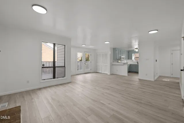 a view of an empty room with wooden floor and a window