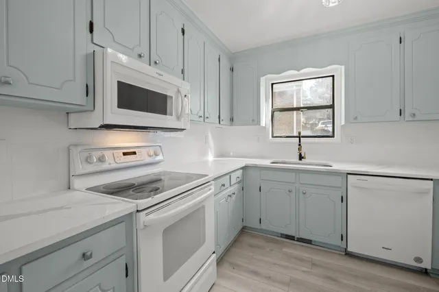 a kitchen with white cabinets and white appliances