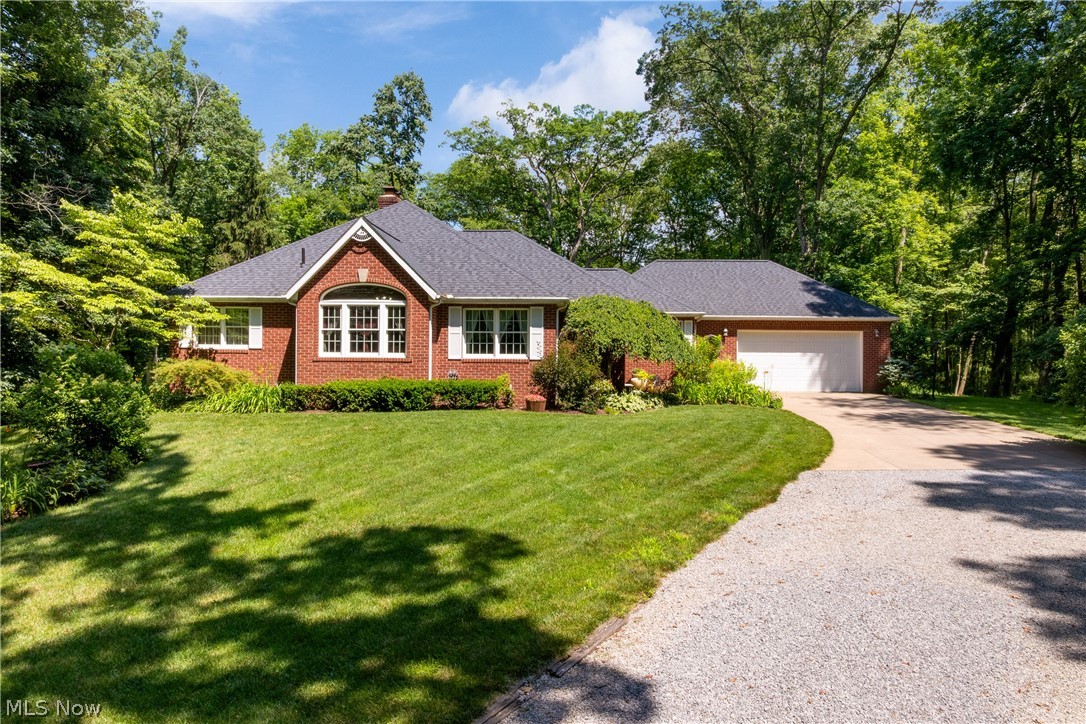 Single story home featuring concrete driveway, a garage, a front yard, a chimney, and brick siding