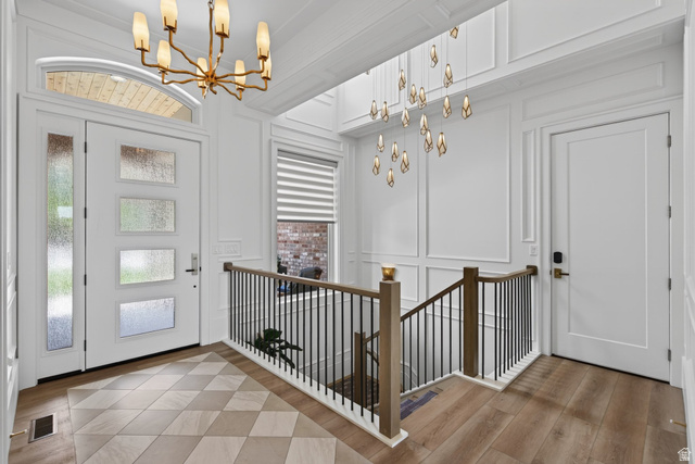 12308 Mariah Circle Draper, UT 84020 - Photo 169 of 293 Guest House Entry foyer featuring a modern front door with sidelight and transom, geometric tile flooring, wood-finish flooring, wainscoting, and a contemporary chandelier