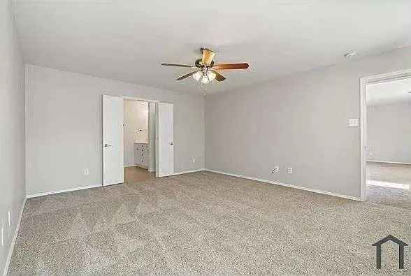 an empty room with windows and fan