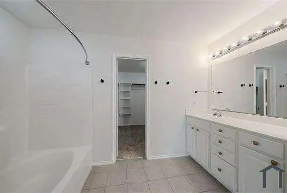 a spacious bathroom with a granite countertop sink a mirror and a bathtub