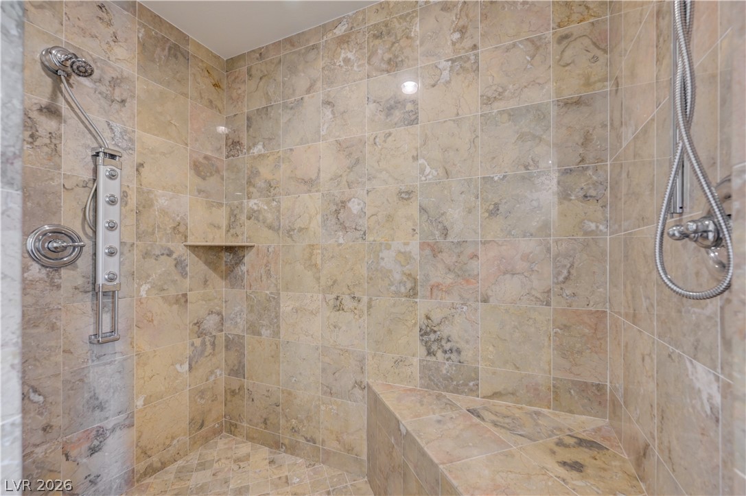 360 East Desert Inn Road, Unit 402 Las Vegas, NV 89109 - Photo 23 of 40 Indulge in a luxurious shower experience with this tastefully tiled enclosure, featuring a built-in bench and dual shower heads.