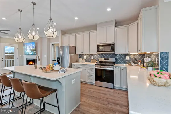 a kitchen with stainless steel appliances granite countertop a stove a sink dishwasher a microwave oven a stove and a dining table with wooden floor