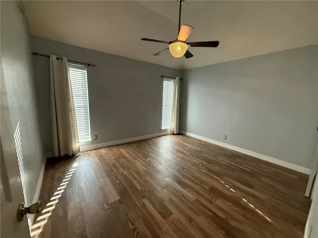 an empty room with wooden floor and windows