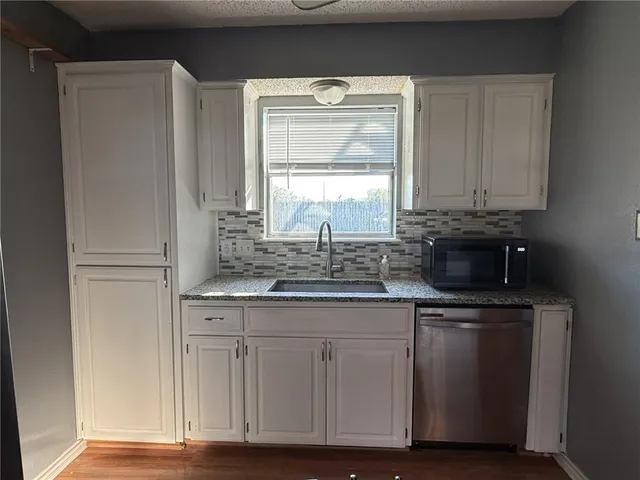 a kitchen with granite countertop a sink and cabinets