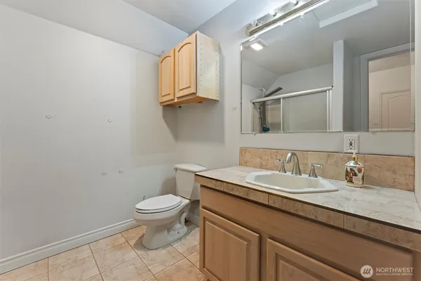 a bathroom with a granite countertop sink a toilet and a mirror