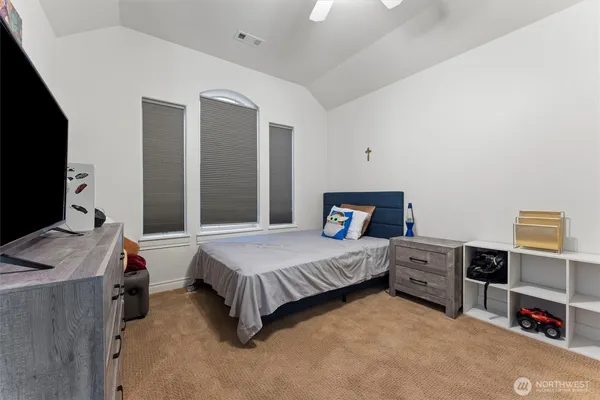 a bedroom with a bed and a flat tv screen on dresser
