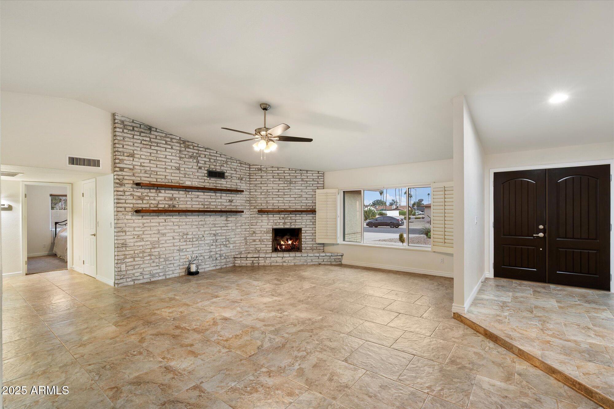 6242 East Hearn Road Scottsdale, AZ 85254 - Photo 6 of 40 a view of an empty room with a fireplace and a chandelier fan