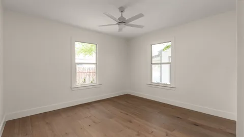 an empty room with wooden floor and windows