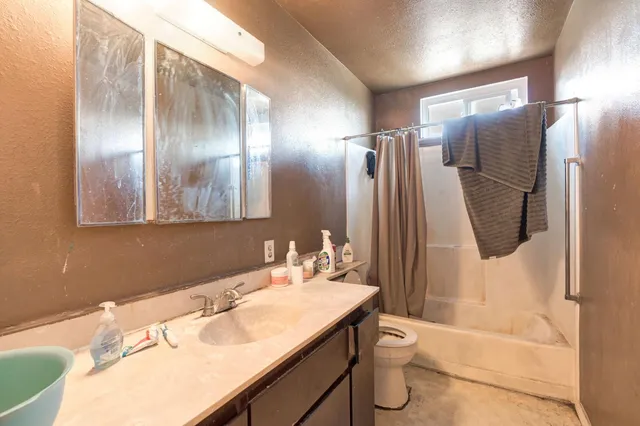 a bathroom with a granite countertop sink a toilet a mirror and shower