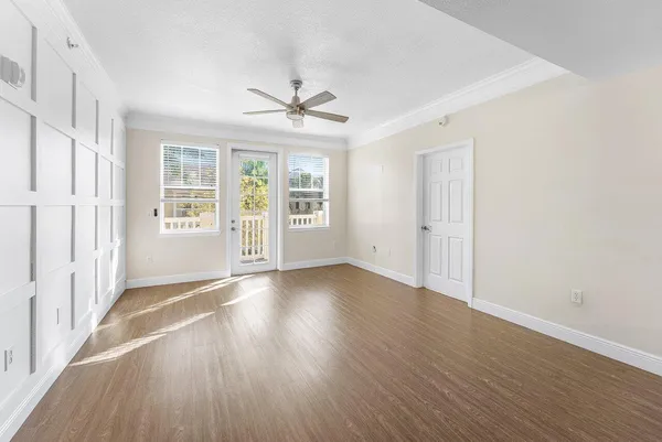 an empty room with wooden floor ceiling fan and windows