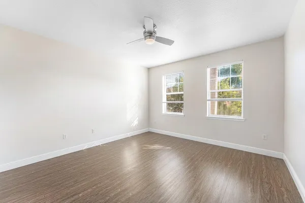 a view of empty room with wooden floor and ceiling fan