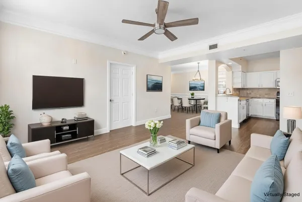 a living room with furniture a flat screen tv and a chandelier