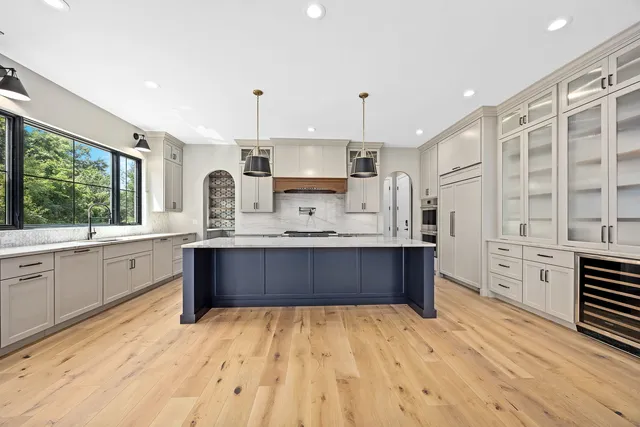 a large kitchen with stainless steel appliances a large counter top a stove a chimney a sink and cabinets