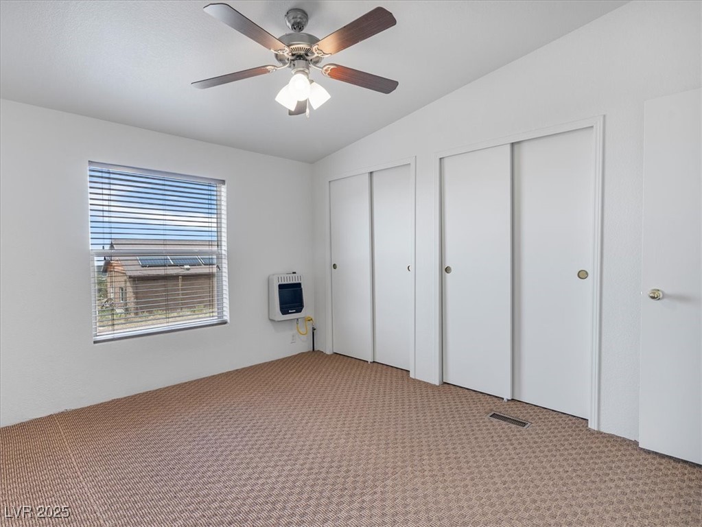 70 West Bonanza Road Las Vegas, NV 89124 - Photo 33 of 71 Unfurnished bedroom featuring heating unit, two closets, carpet floors, lofted ceiling, and a ceiling fan