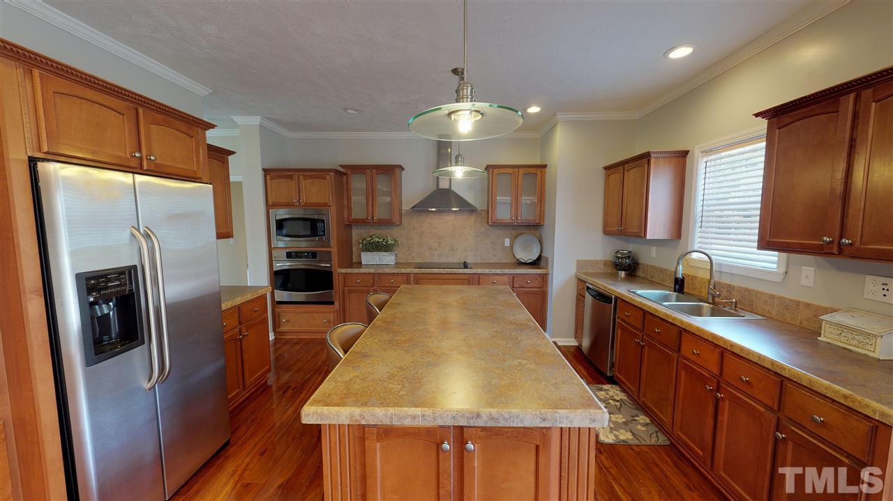 1920 Sanders Road Willow Spring, NC 27592 - Photo 12 of 29 a kitchen with stainless steel appliances granite countertop a refrigerator a sink dishwasher a stove and a dining table with wooden floor