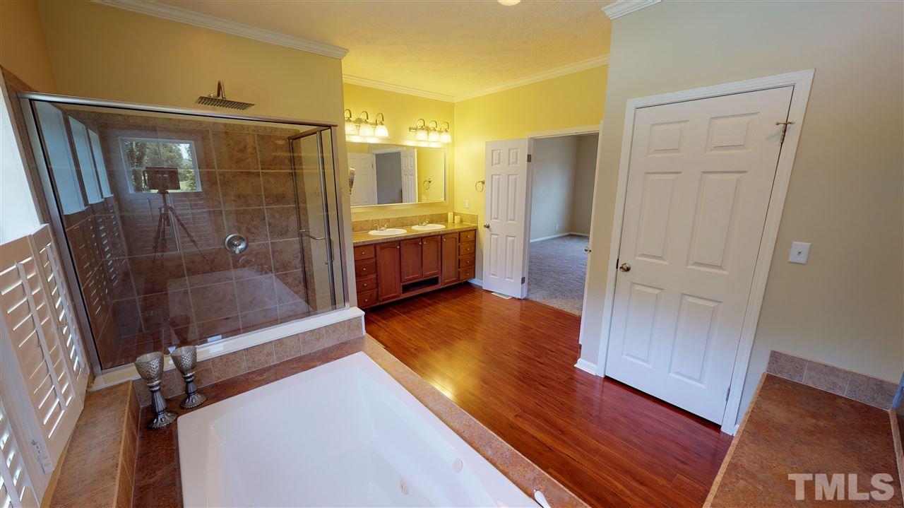 1920 Sanders Road Willow Spring, NC 27592 - Photo 16 of 29 a bathroom with a glass door shower a sink and a mirror