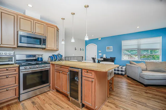 a open kitchen with stainless steel appliances granite countertop a stove a sink dishwasher and a microwave oven with wooden floor