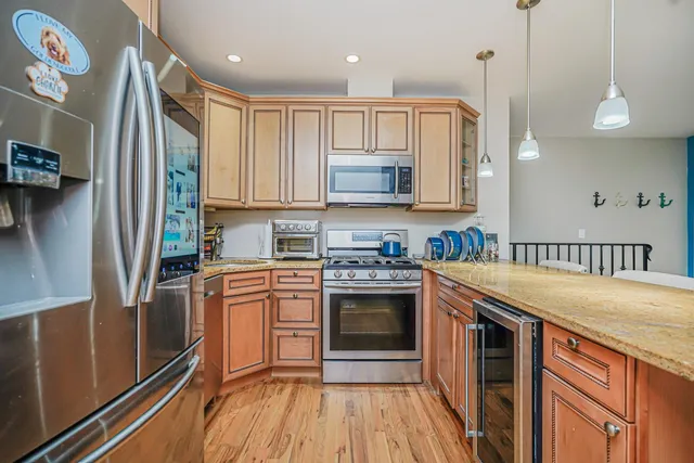 a kitchen with stainless steel appliances granite countertop a stove a sink and a refrigerator with wooden floor