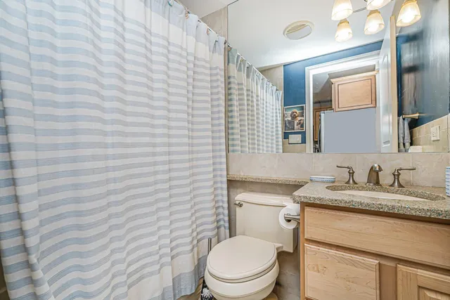 a bathroom with a granite countertop toilet sink and mirror