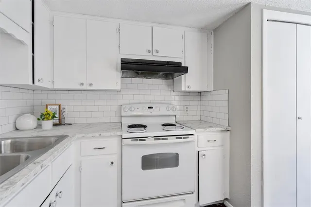 a kitchen with granite countertop white cabinets and white appliances