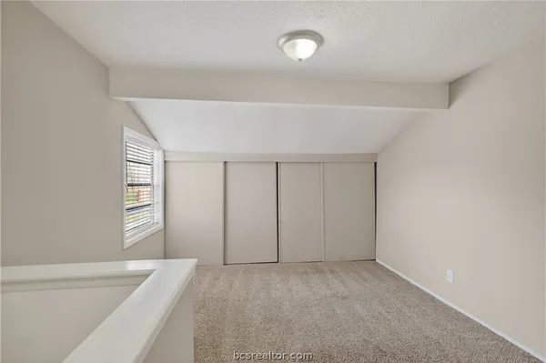 a view of an empty room with closet and windows