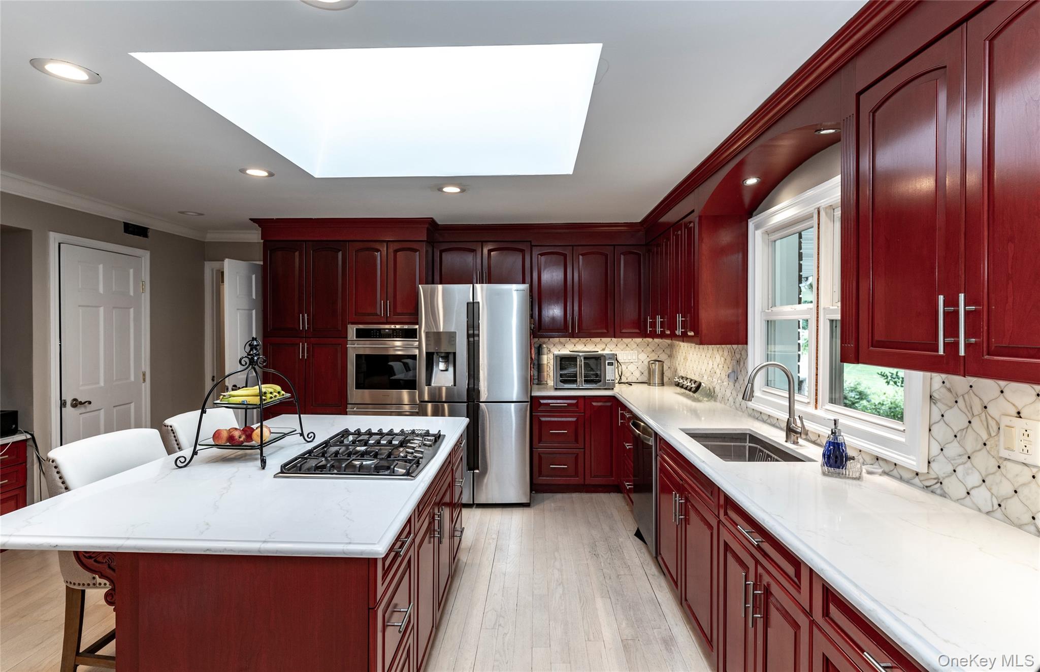 369 Phillips Hill Road New City, NY 10956 - Photo 13 of 40 Kitchen with reddish brown cabinets, ornamental molding, a skylight, a kitchen breakfast bar, and backsplash