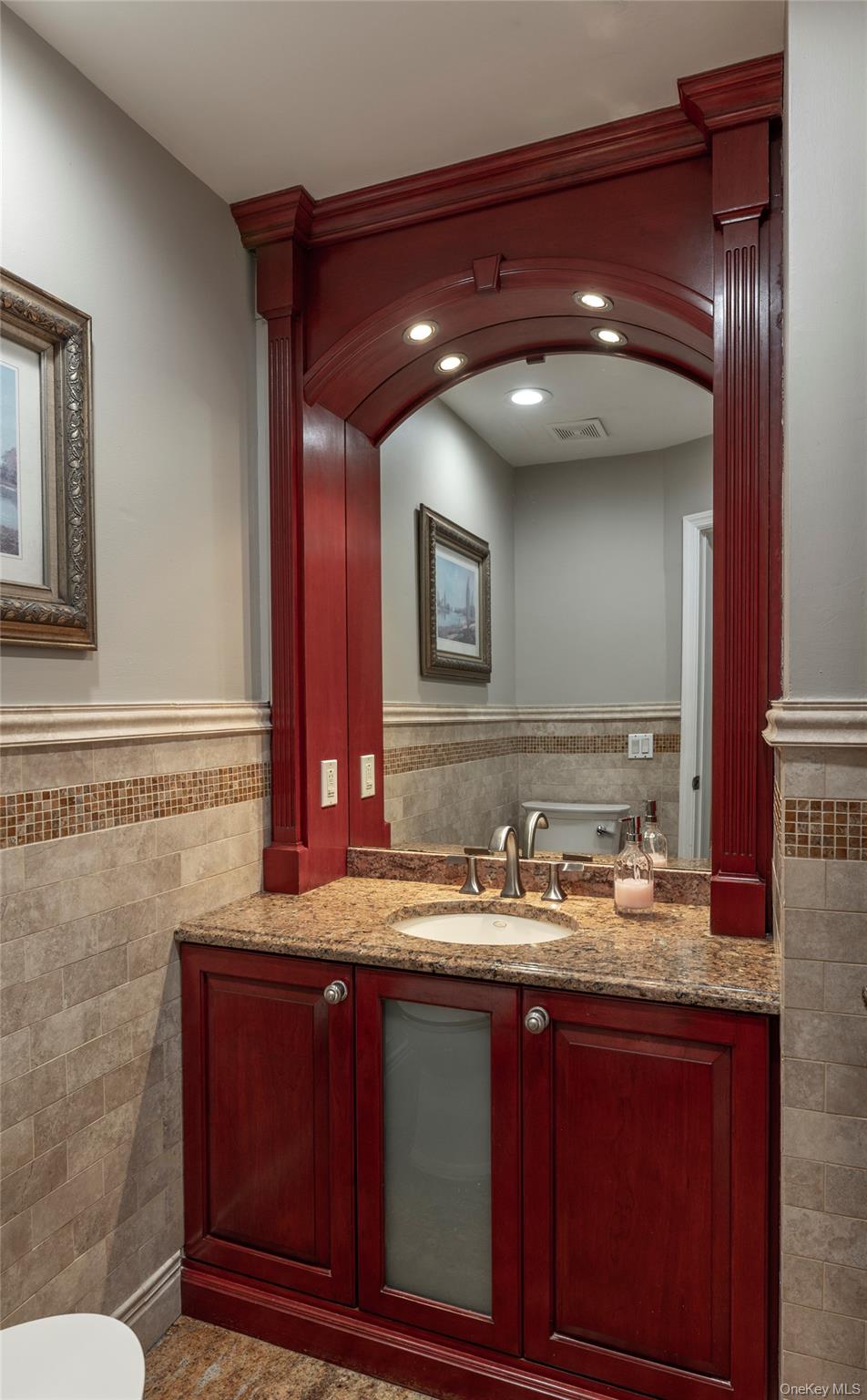 369 Phillips Hill Road New City, NY 10956 - Photo 32 of 40 Half bath with tile walls, wainscoting, vanity, and recessed lighting