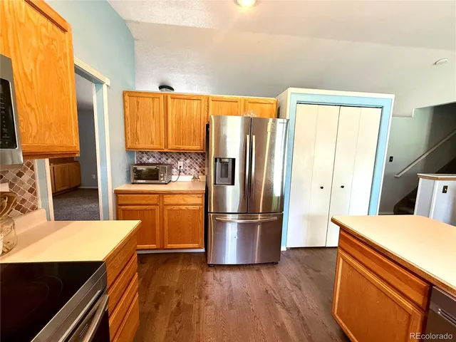 a kitchen with stainless steel appliances a refrigerator and wooden floor
