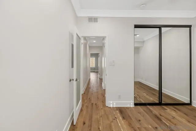 a view of a hallway with wooden floor and a bathroom