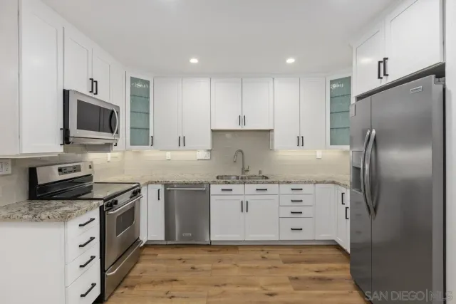 a kitchen with stainless steel appliances granite countertop a stove top oven a sink and a refrigerator