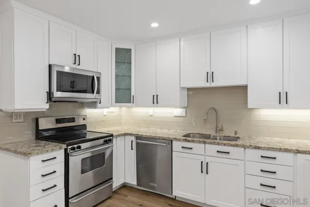 a kitchen with granite countertop white cabinets and stainless steel appliances