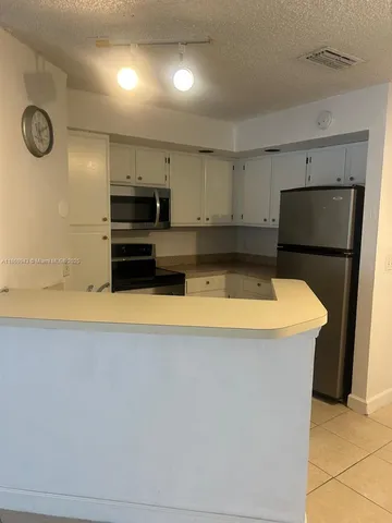 a kitchen with a refrigerator and a stove top oven