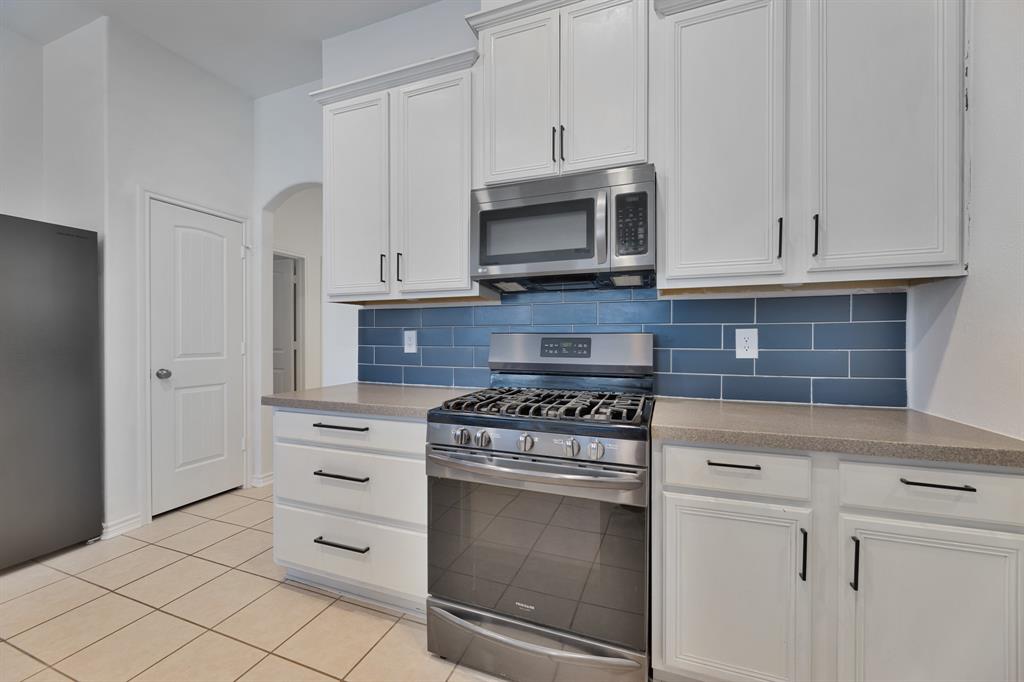 5129 Leeray Road Fort Worth, TX 76244 - Photo 28 of 39 a kitchen with white cabinets and appliances