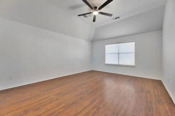 an empty room with wooden floor fan and windows