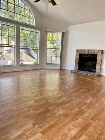 an empty room with wooden floor fireplace and windows