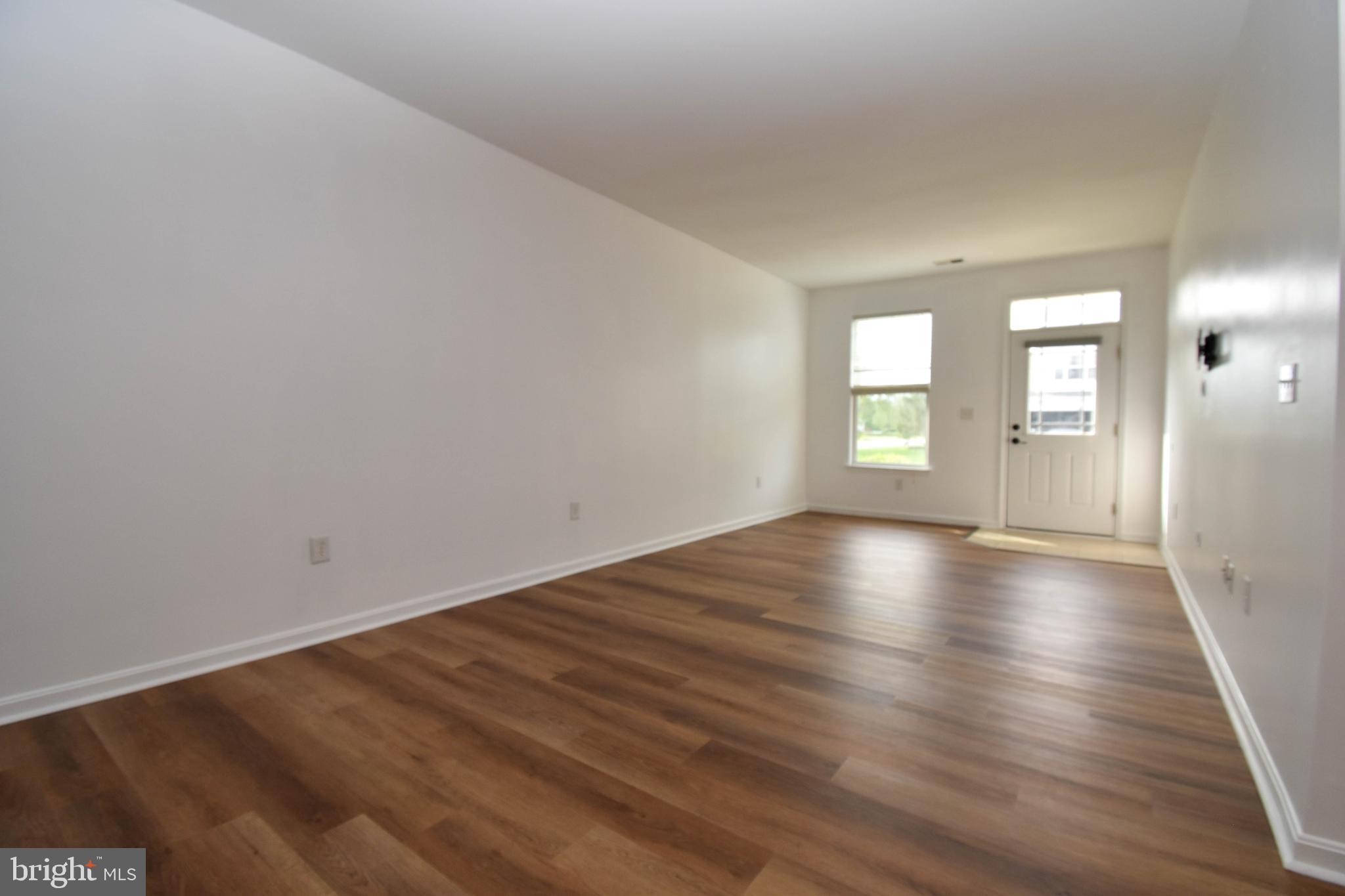 29549 Whitstone Lane, Unit 1305 Millsboro, DE 19966 - Photo 3 of 31 wooden floor in an empty room with a window