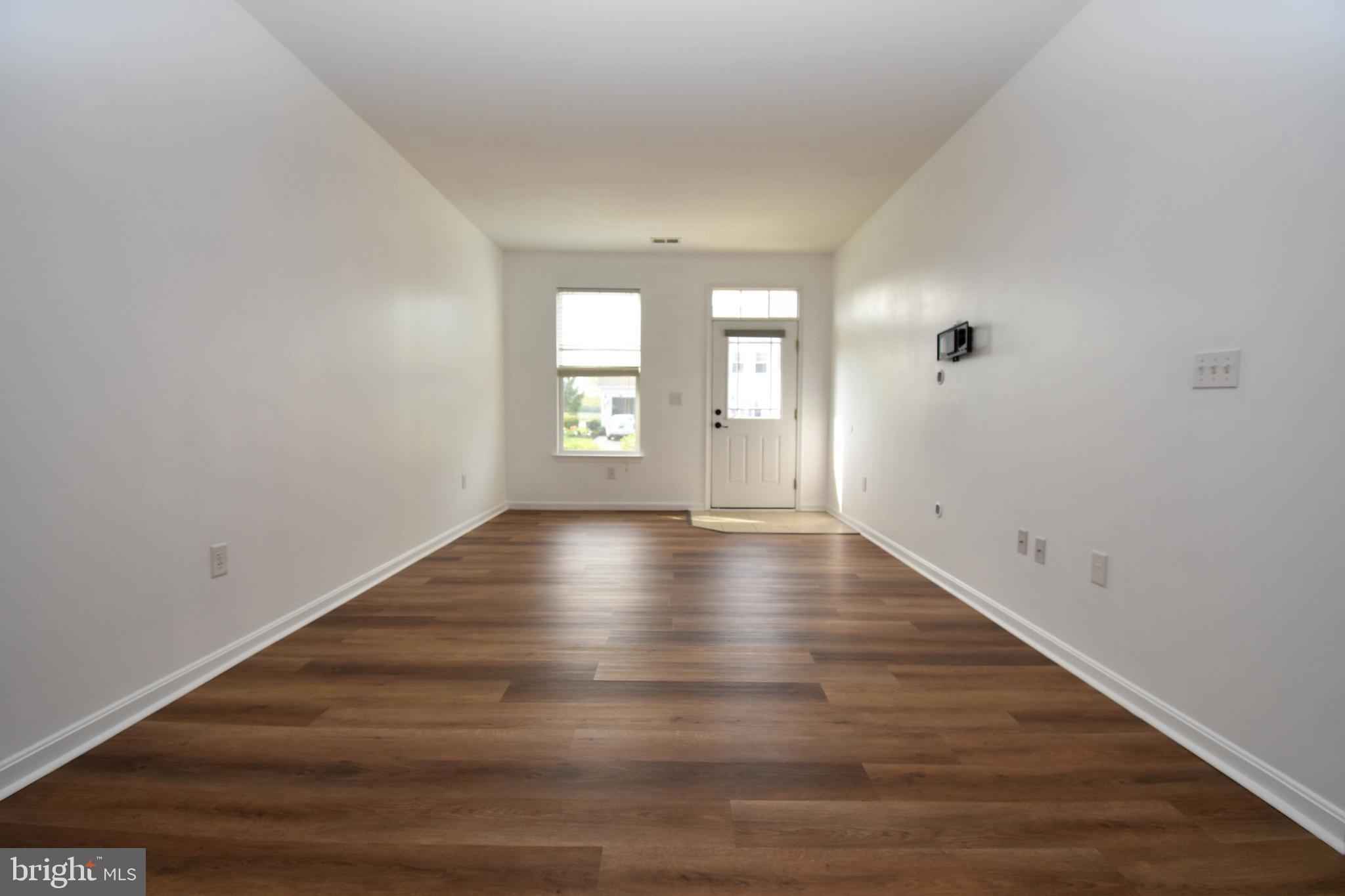 29549 Whitstone Lane, Unit 1305 Millsboro, DE 19966 - Photo 6 of 31 wooden floor in an empty room with a window