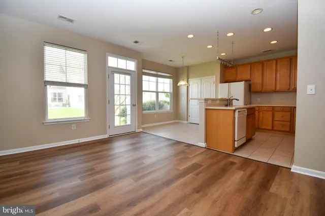 an open kitchen with a refrigerator and wooden floor