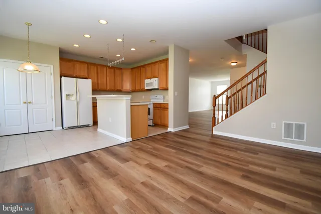 a view of an empty room with kitchen and window