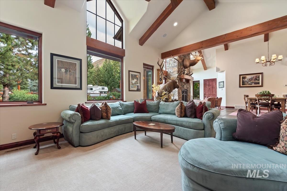 106 Hidden Hollow Road Hailey, ID 83333 - Photo 26 of 49 Vaulted ceiling with exposed wood beams, large windows, stone-clad fireplace, and a dining area with a chandelier
