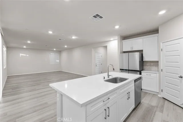 a kitchen with a sink dishwasher and white cabinets with wooden floor