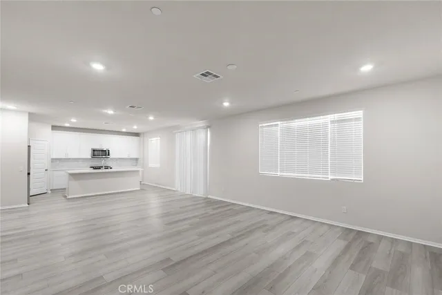 a view of kitchen with kitchen island a sink wooden floor and a living room view
