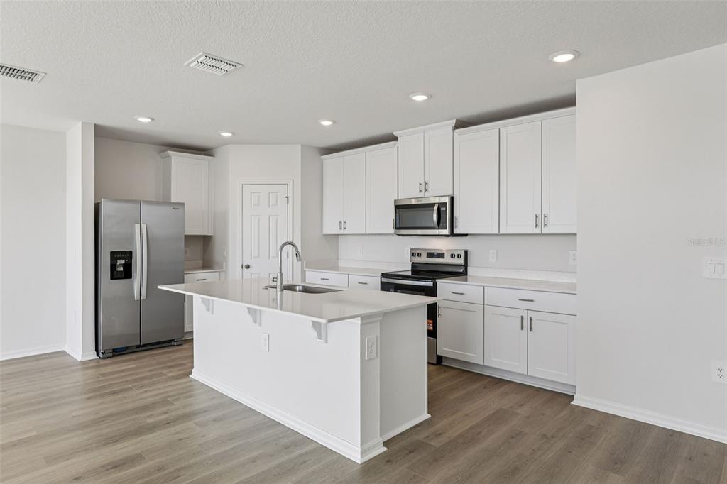 4018 Copperleaf Lane Kissimmee, FL 34759 - Photo 11 of 36 a kitchen with white cabinets and stainless steel appliances