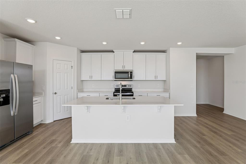 4018 Copperleaf Lane Kissimmee, FL 34759 - Photo 12 of 36 a large kitchen with stainless steel appliances granite countertop a stove a refrigerator a sink and a oven with wooden floor
